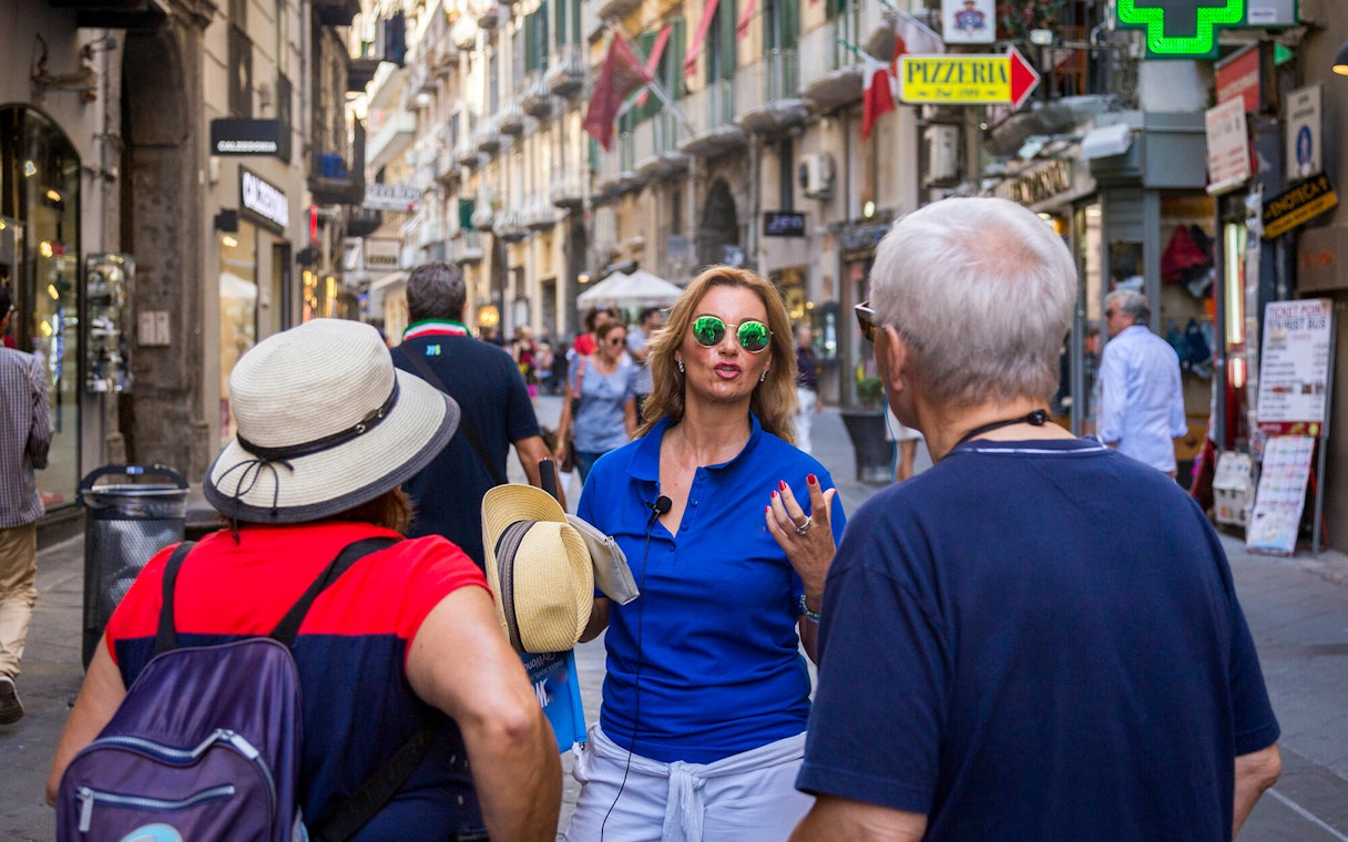Tour group with guide walking through a busy street in Naples.