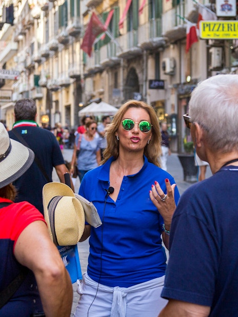 Tour group with guide walking through a busy street in Naples.