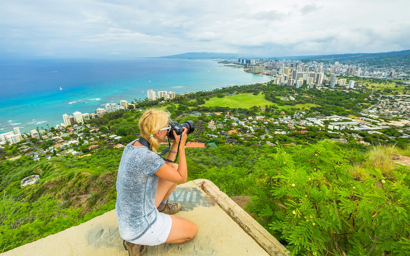 A woman photographing the view from Diamond head lookout point, Hawaii