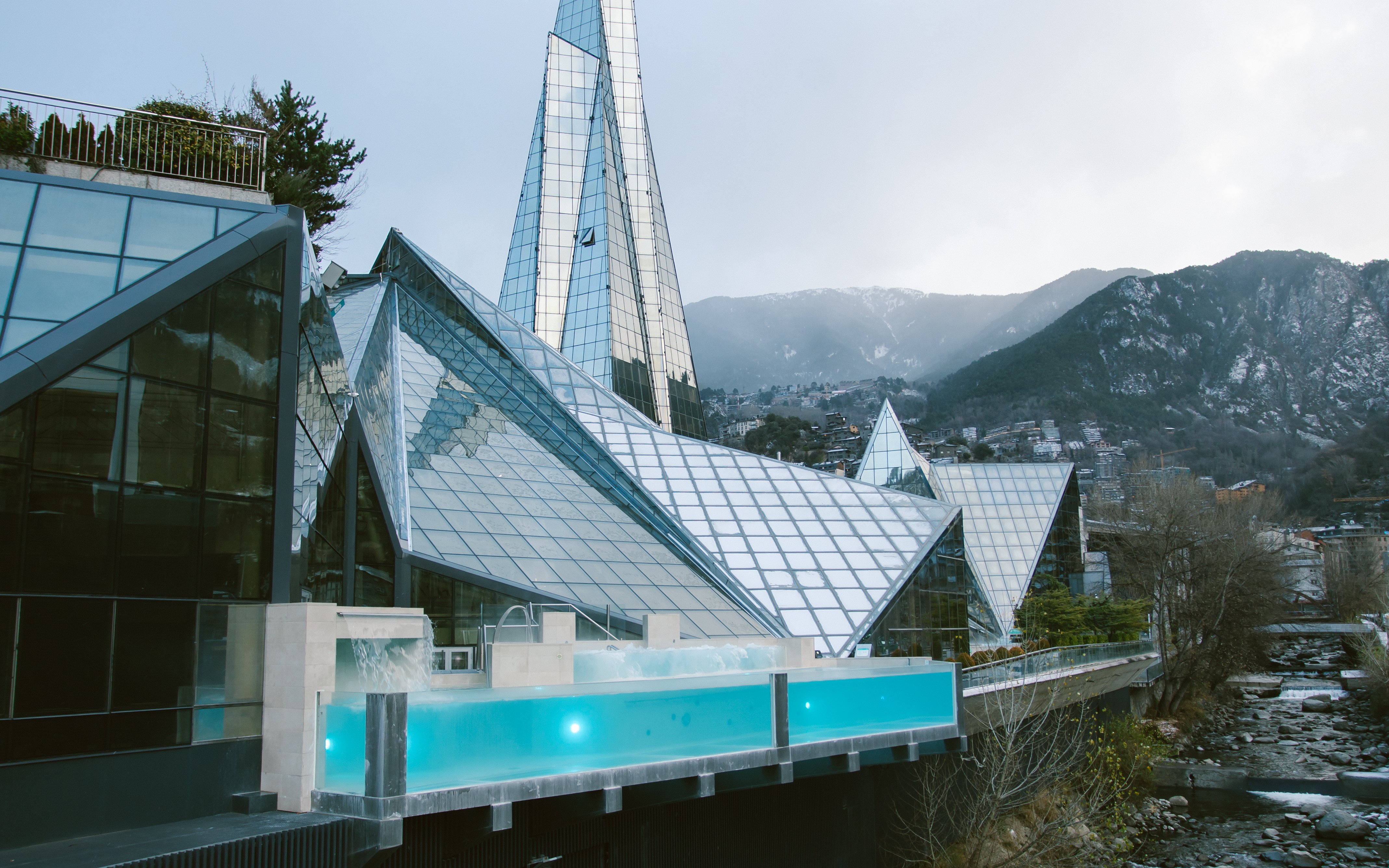 Caldea spa's glass tower in Andorra with mountain backdrop.