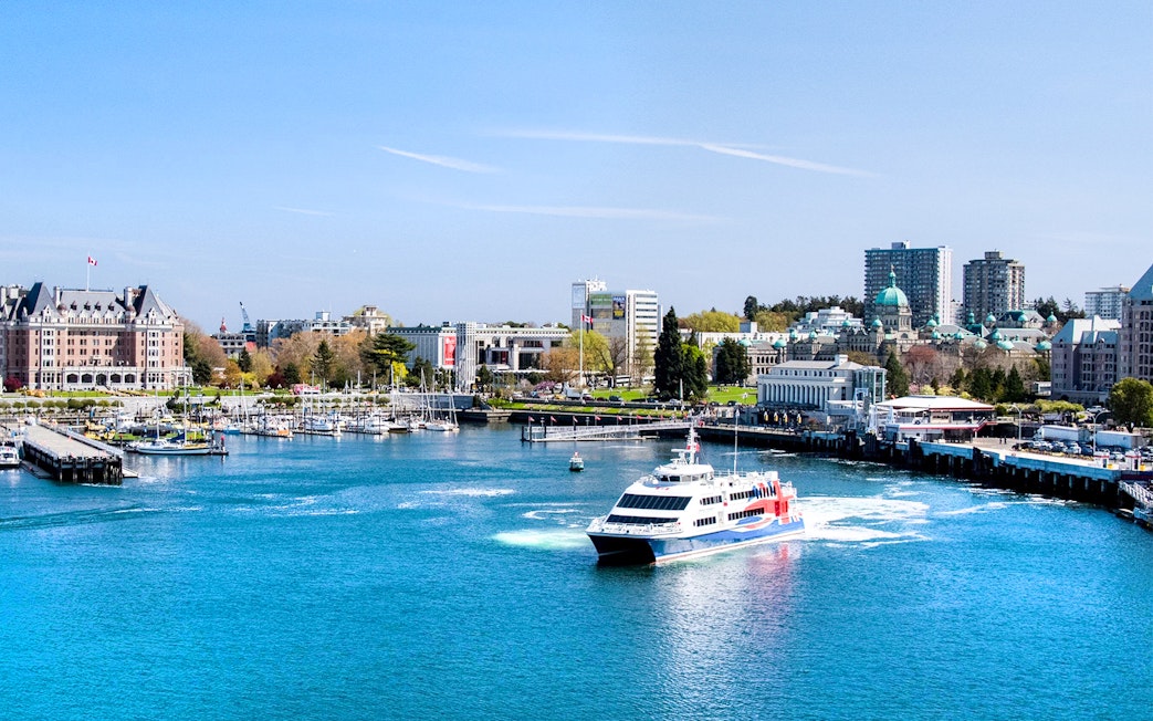 High-speed ferry approaching Victoria, BC harbor with cityscape and Parliament Buildings in view.