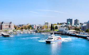 High-speed ferry approaching Victoria, BC harbor with cityscape and Parliament Buildings in view.