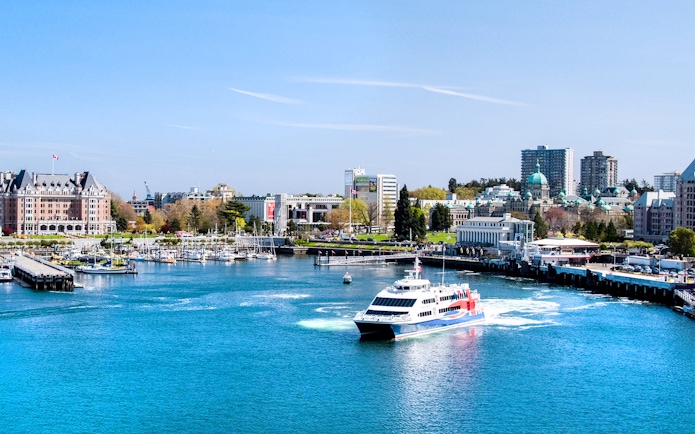 High-speed ferry approaching Victoria, BC harbor with cityscape and Parliament Buildings in view.
