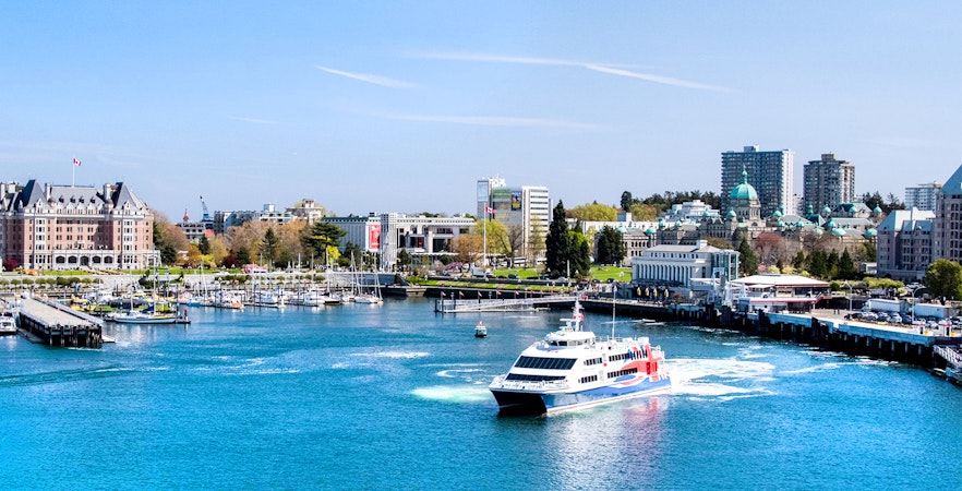 High-speed ferry approaching Victoria, BC harbor with cityscape and Parliament Buildings in view.