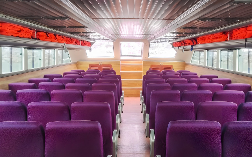 Interior seating of boat from Bali to Nusa Penida with purple seats and life jackets.
