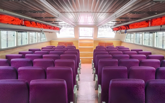 Interior seating of boat from Bali to Nusa Penida with purple seats and life jackets.