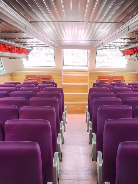 Interior seating of boat from Bali to Nusa Penida with purple seats and life jackets.