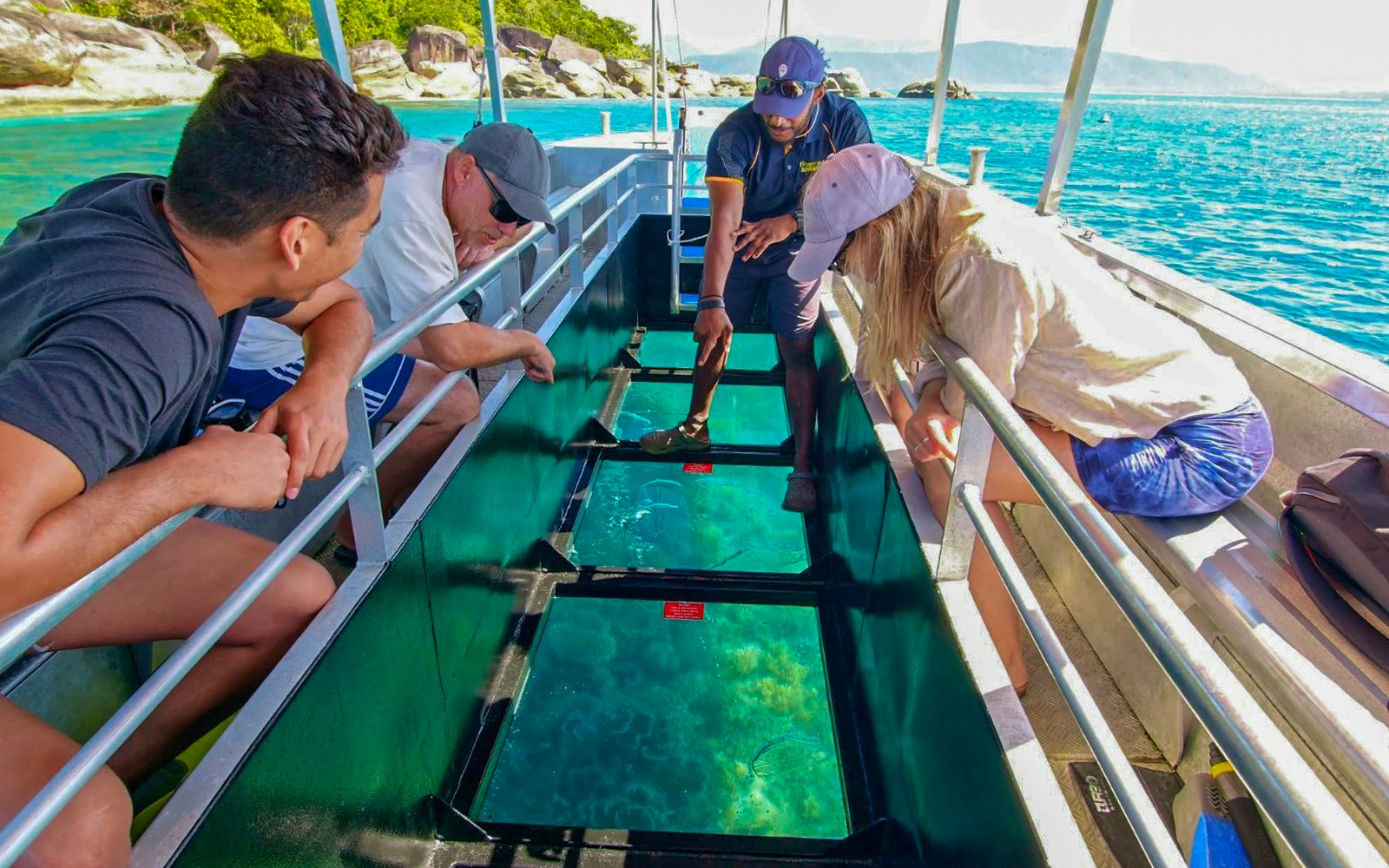 Tourists on a glass bottom boat viewing marine life during Fitzroy Island tour from Cairns.