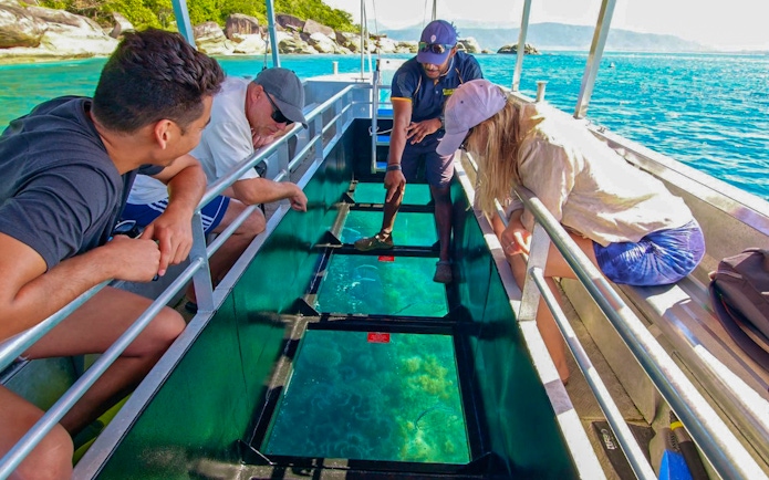 Tourists on a glass bottom boat viewing marine life during Fitzroy Island tour from Cairns.