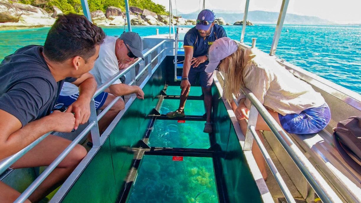 Tourists on a glass bottom boat viewing marine life during Fitzroy Island tour from Cairns.