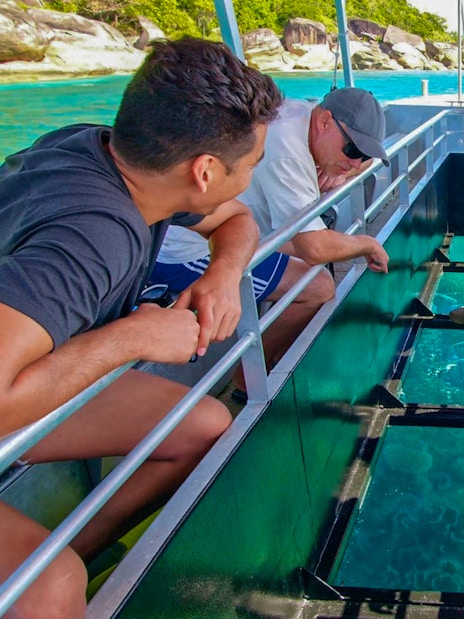 Tourists on a glass bottom boat viewing marine life during Fitzroy Island tour from Cairns.