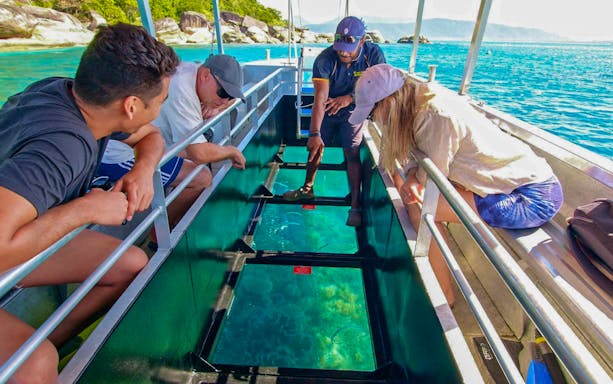 Tourists on a glass bottom boat viewing marine life during Fitzroy Island tour from Cairns.