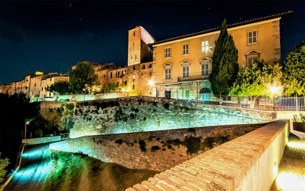 Night view of Museum of San Pietro in Colle Val d'Elsa with illuminated historic buildings.