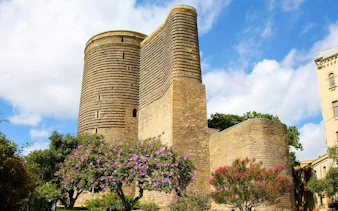 Maiden Tower Museum in Baku with blooming trees in the foreground.