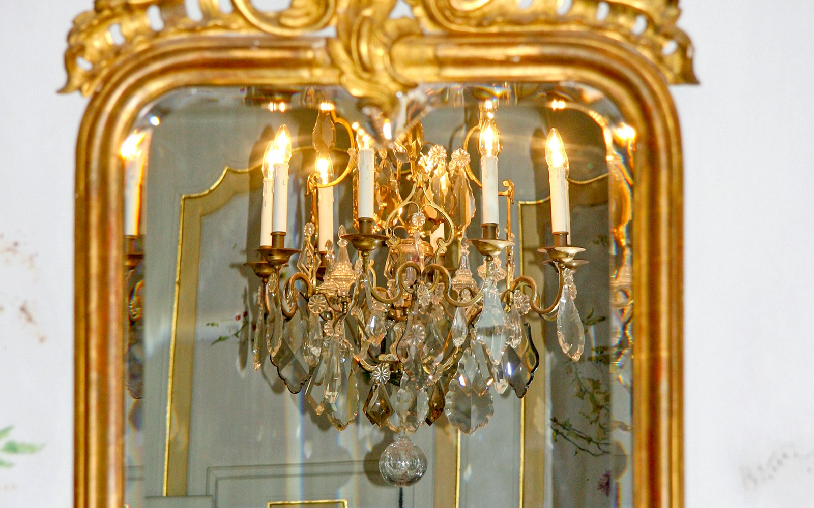 Reflection of chandelier in an ornate antique mirror.