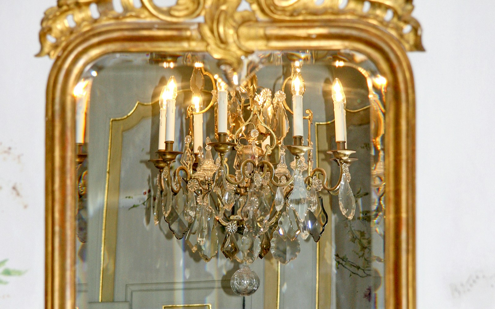 Reflection of chandelier in an ornate antique mirror.