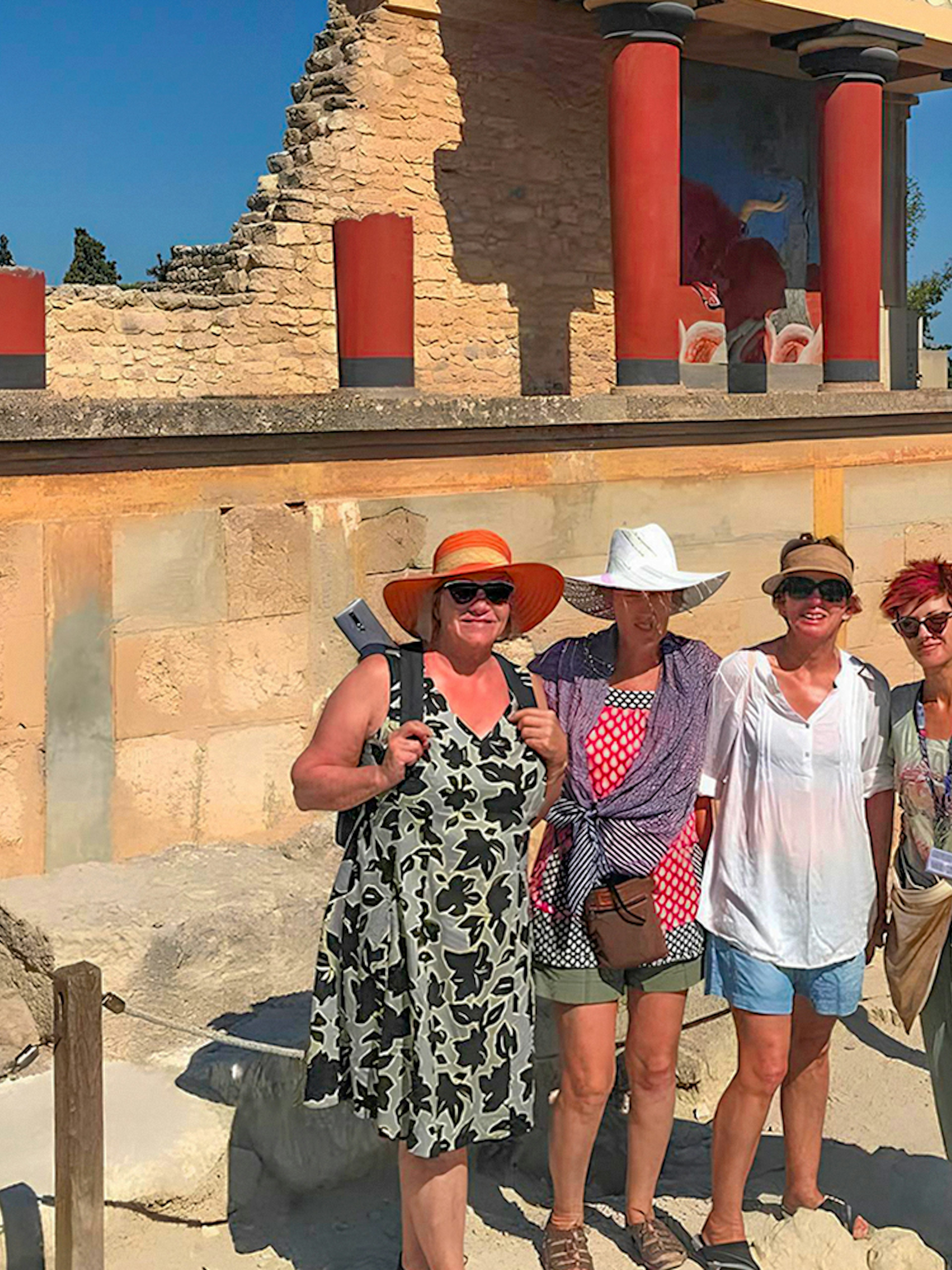 Guests exploring Knossos Palace ruins with frescoes and columns in Crete.