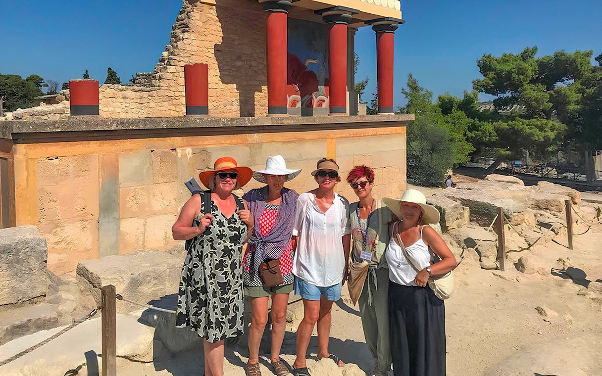 Guests exploring Knossos Palace ruins with frescoes and columns in Crete.