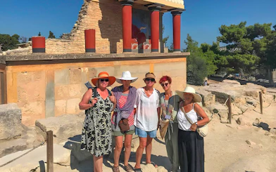 Guests exploring Knossos Palace ruins with frescoes and columns in Crete.