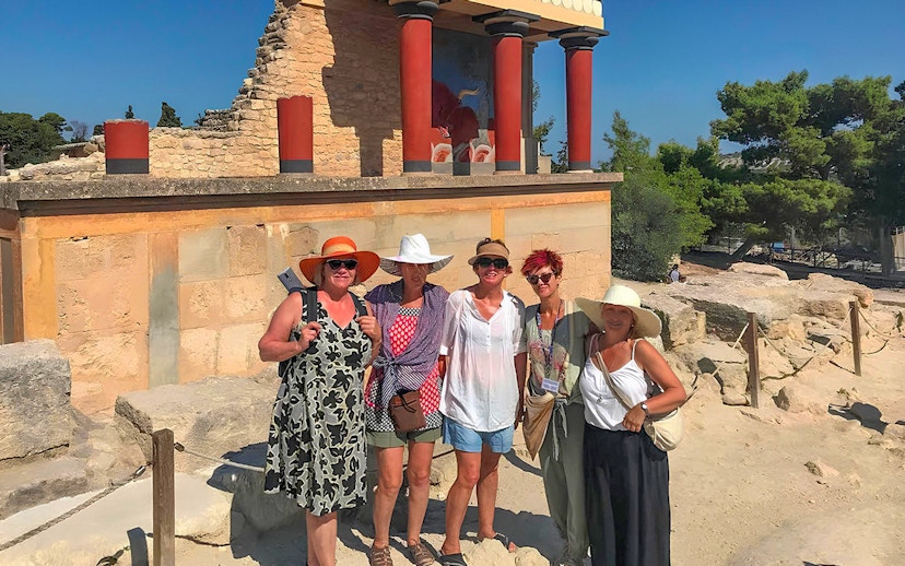Guests exploring Knossos Palace ruins with frescoes and columns in Crete.