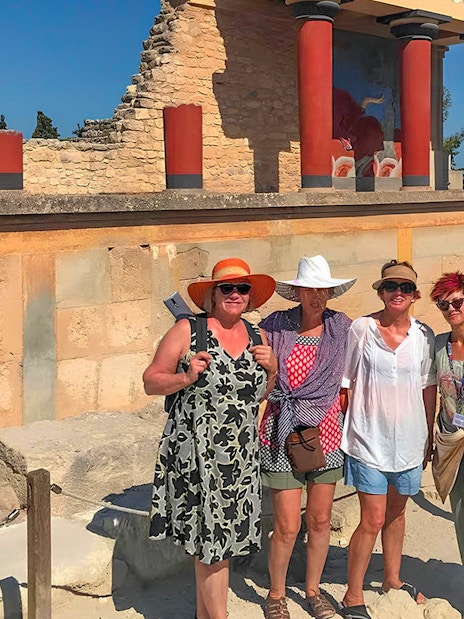 Guests exploring Knossos Palace ruins with frescoes and columns in Crete.