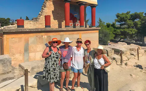 Guests exploring Knossos Palace ruins with frescoes and columns in Crete.