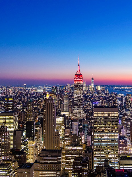 New York City skyline at night from SUMMIT One Vanderbilt, featuring illuminated skyscrapers.