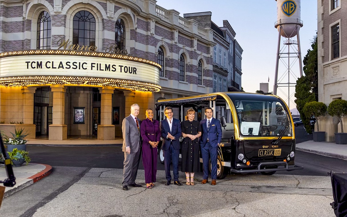 Warner Bros. Studio entrance with TCM Classic Films Tour sign and tour group.