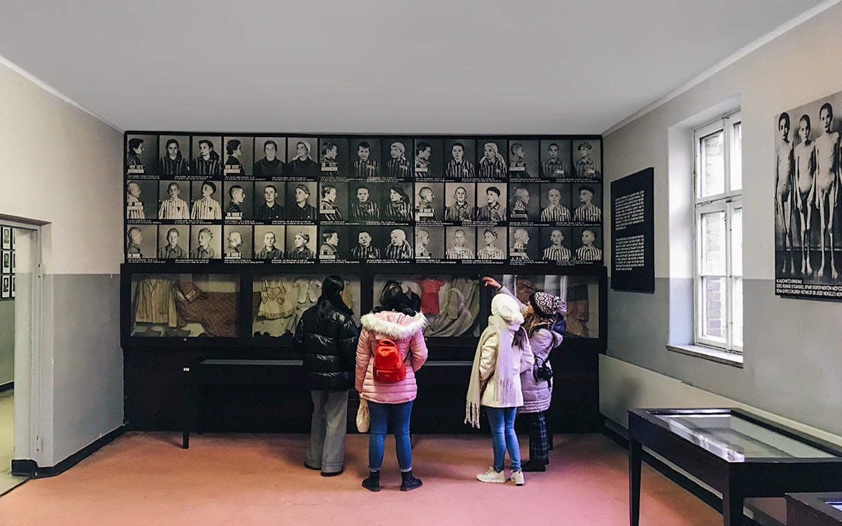 Visitors viewing Holocaust photos at Auschwitz museum exhibit.