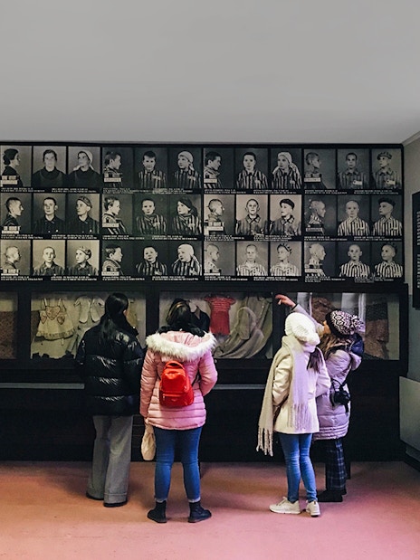 Visitors viewing Holocaust photos at Auschwitz museum exhibit.
