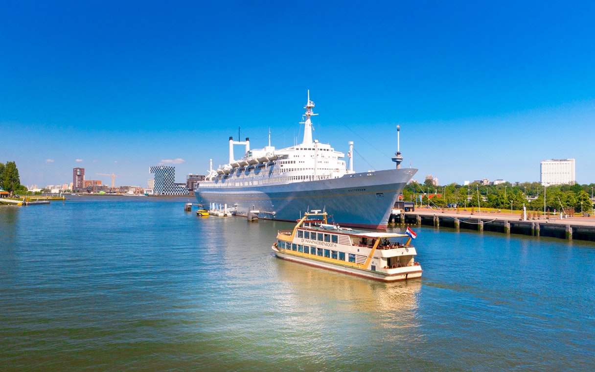Pancake Cruise boat on Rotterdam harbor with a large ship in the background.