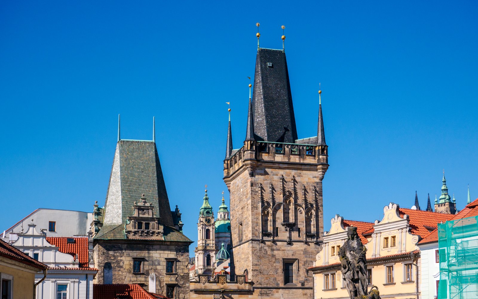 Lesser Town Bridge Tower in Prague with historic architecture and blue sky.