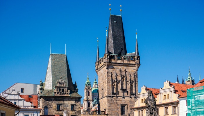 Lesser Town Bridge Tower in Prague with historic architecture and blue sky.