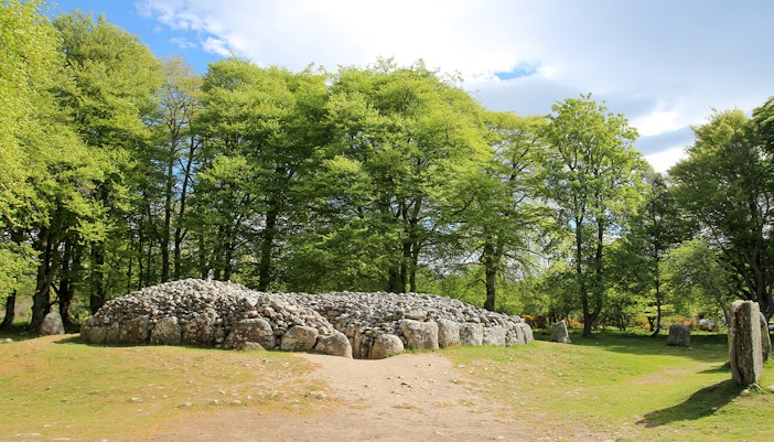 Ancient stone cairn surrounded by trees at Clava Cairns, Scotland.