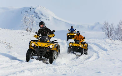 ATVs driving through snowy terrain with mountain backdrop on Twin Peaks tour, Reykjavik.