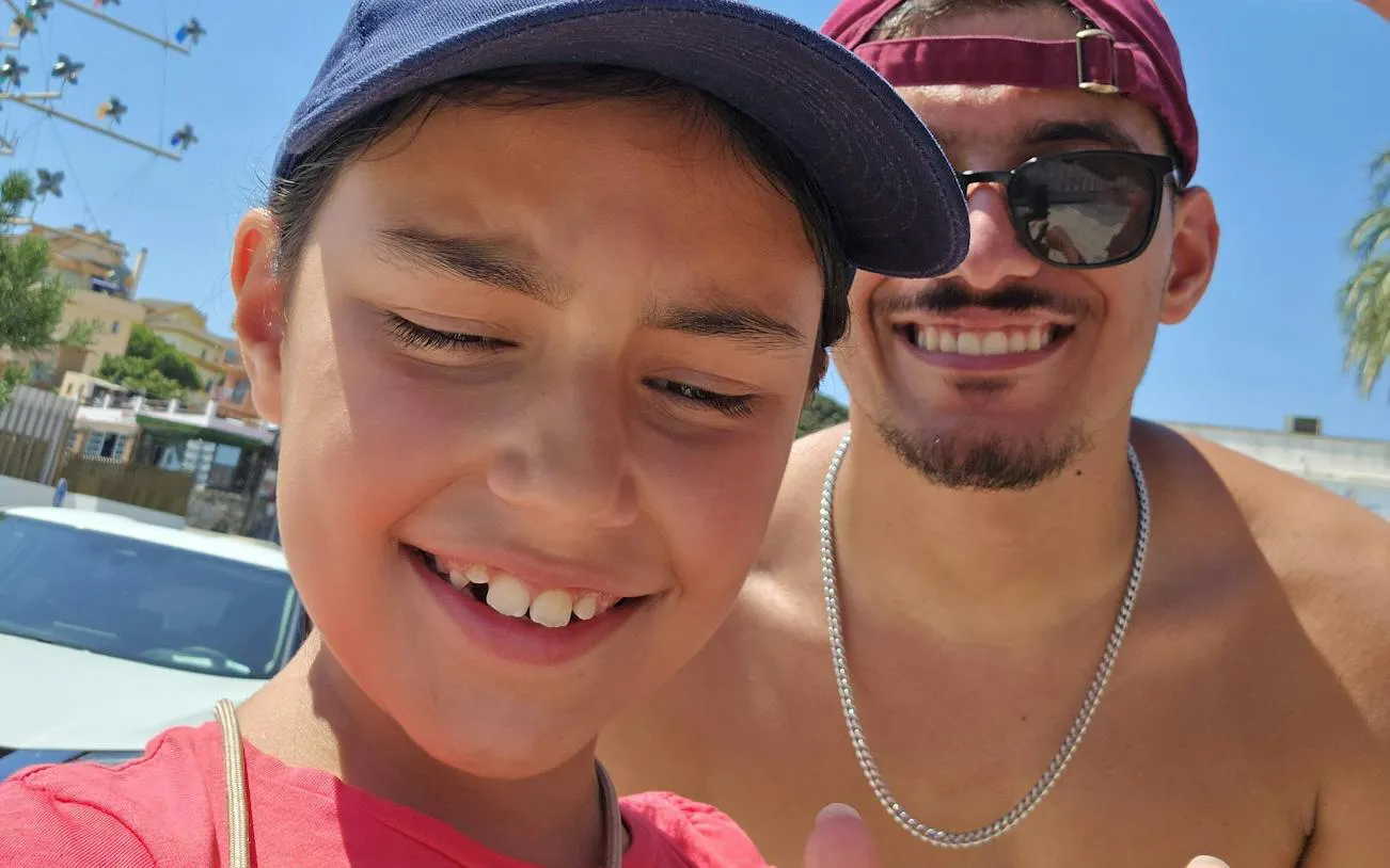 Selfie during Benalmádena Pueblo exploration game, with buildings and palm trees in the background.