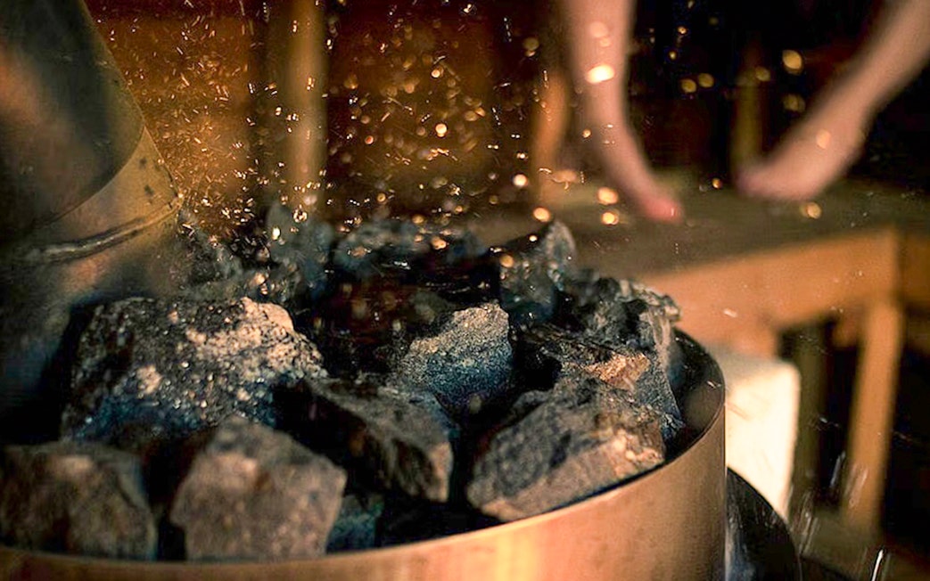 Burning coals and salts in a sauna during Northern Lights experience in Rovaniemi.