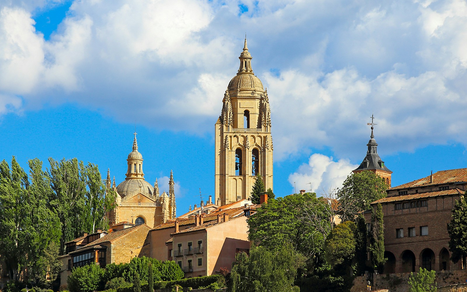 Segovia Cathedral bell tower against a blue sky with surrounding architecture.