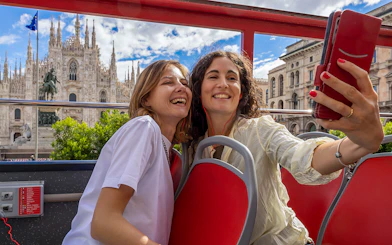 Tourists taking selfie with Milan Cathedral from City Sightseeing bus.