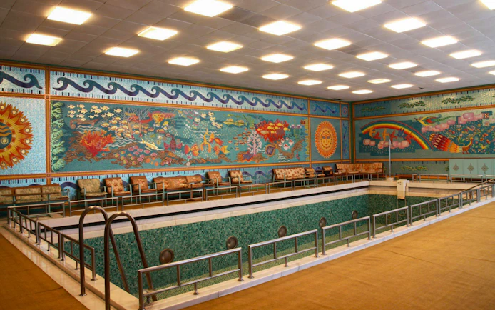 Indoor pool with mosaic walls depicting aquatic scenes inside Ceausescu Mansion, Bucharest.