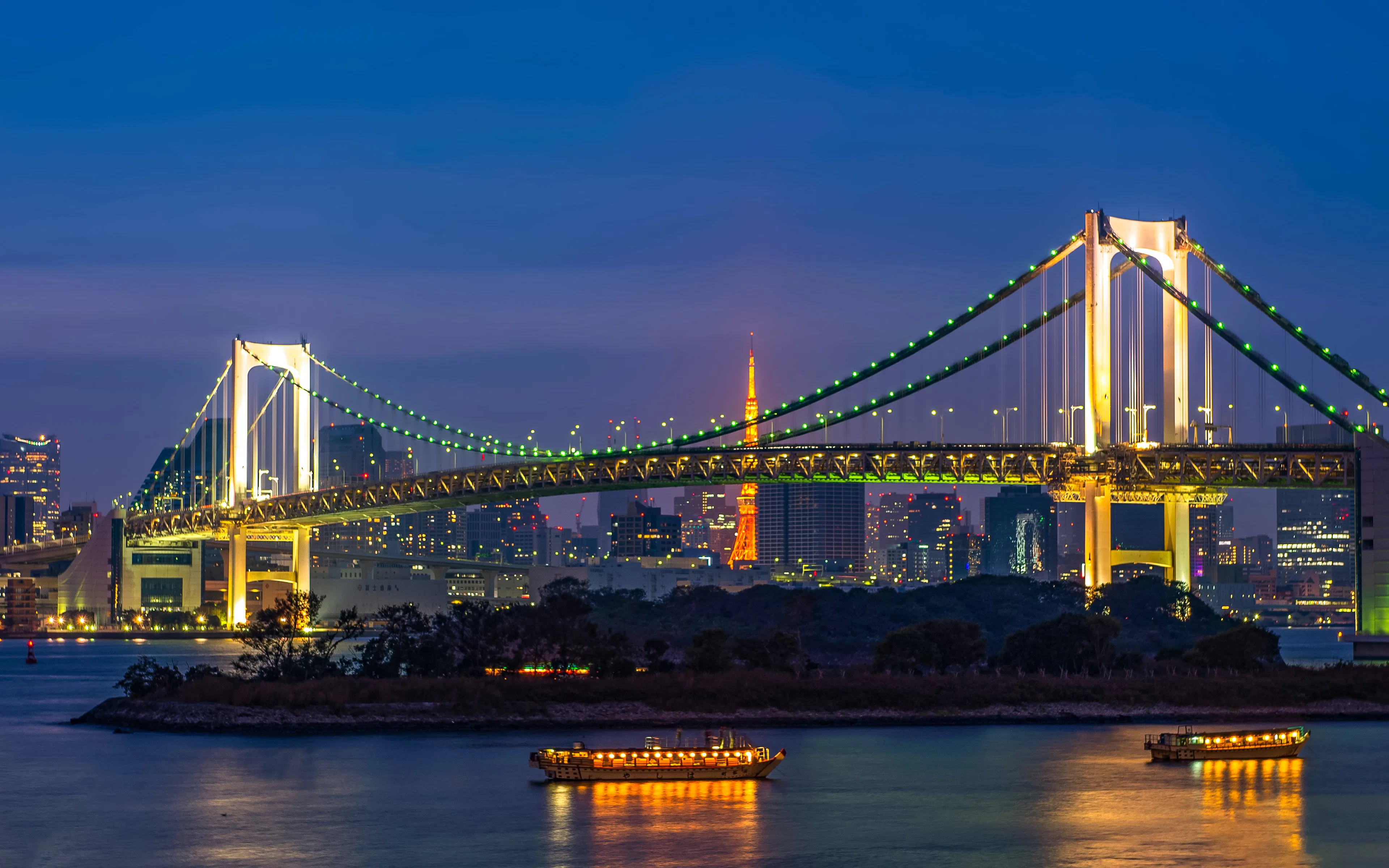 Tokyo Tower and Rainbow Bridge illuminated at sunset, Odaiba, Tokyo, Japan.