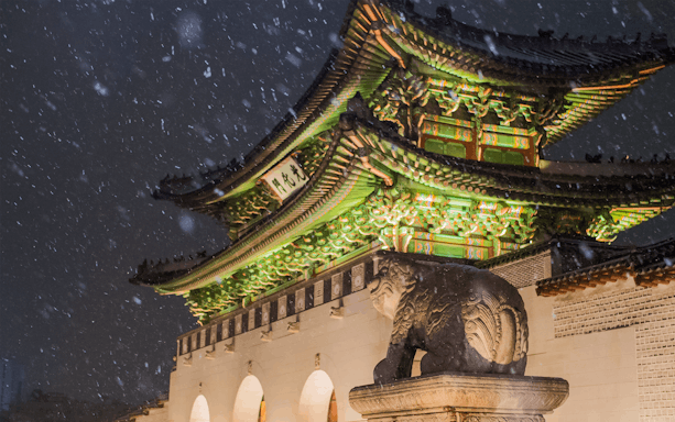 Gyeongbokgung Palace gate illuminated at night with snow falling, Seoul, South Korea.