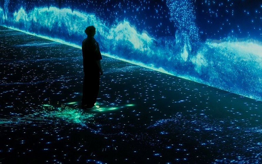 Person standing in immersive digital ocean display at Arte Museum, New York.