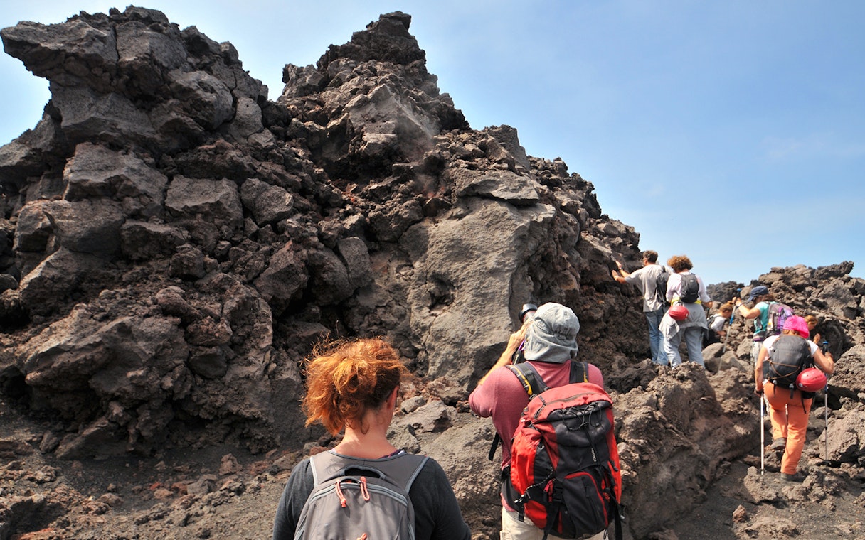 Hikers exploring lava rock formations at Mount Etna.