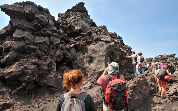 Hikers exploring lava rock formations at Mount Etna.