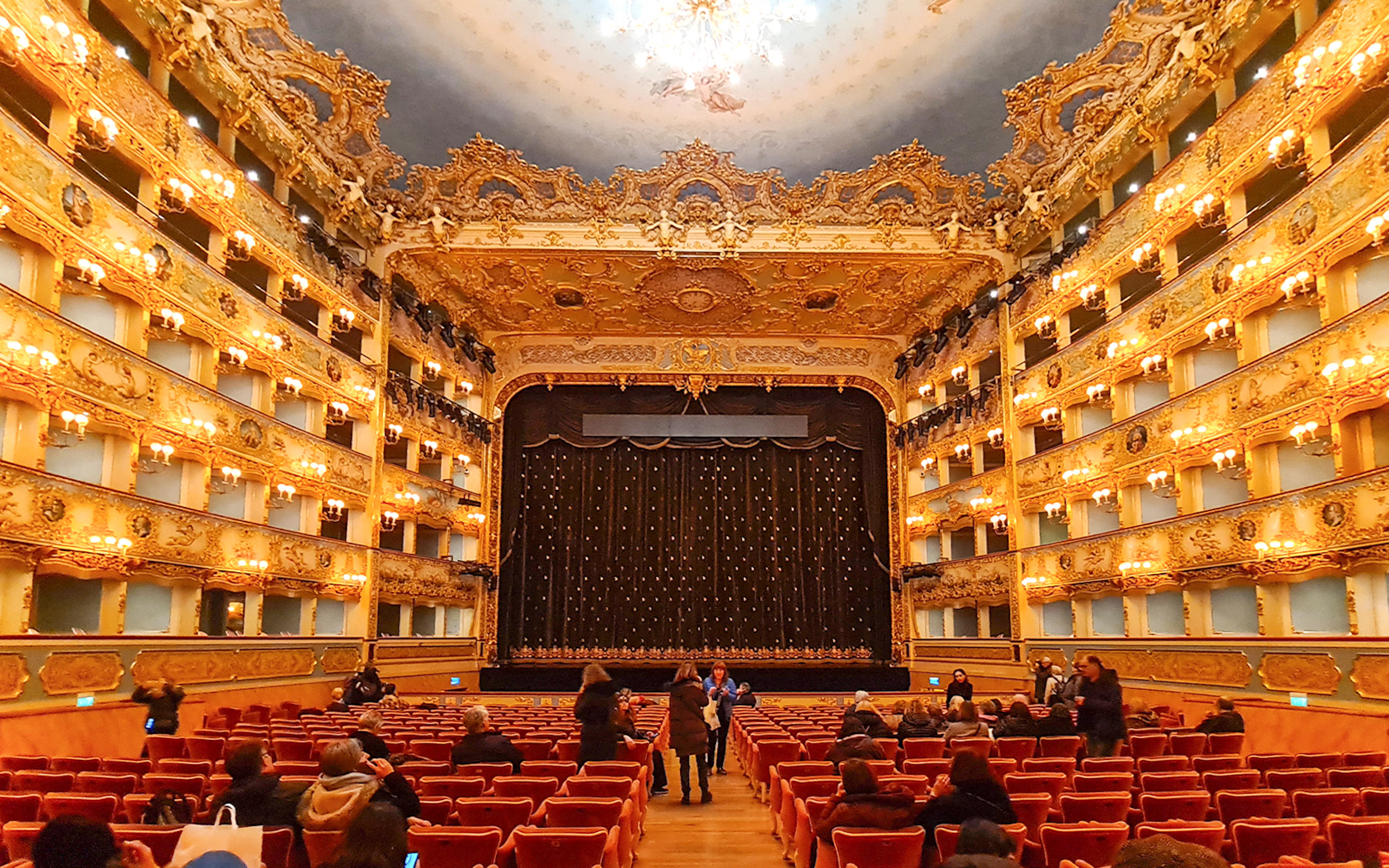 Teatro La Fenice interior with ornate balconies and stage curtain in Venice, Italy.