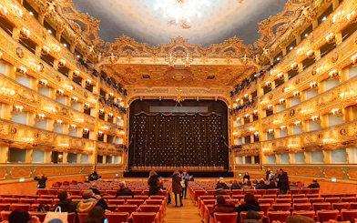 Teatro La Fenice interior with ornate balconies and stage curtain in Venice, Italy.