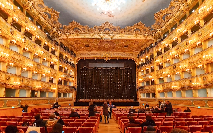 Teatro La Fenice interior with ornate balconies and stage curtain in Venice, Italy.