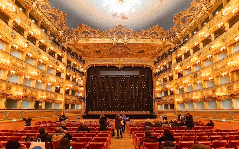 Teatro La Fenice interior with ornate balconies and stage curtain in Venice, Italy.