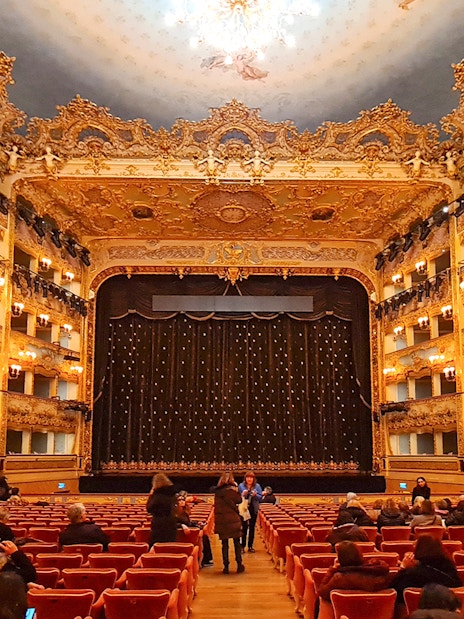 Teatro La Fenice interior with ornate balconies and stage curtain in Venice, Italy.